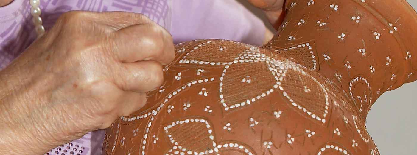 A operária introduz as pedrinhas de quartzo ao longo dos riscos feitos na peça, sempre com a parte mais pontiaguda para dentro e depois pressiona-as com a unha do polegar.
